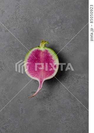 Half Lobo Margelian radish with a pink center. Close-up on a gray background. Vertical with space. 85050923