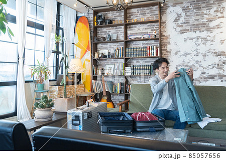 出張 旅行 断捨離 リビングでスーツケースに服を詰める若い男性 出張 旅行 断捨離 リビングでスーツケースに服を詰める若い男性 85057656