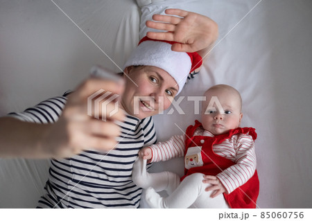 Loving young mommy making a selphie with a adorable sweet baby girl lying in bed. Loving young mommy making a selphie with a adorable sweet baby girl lying in bed. 85060756