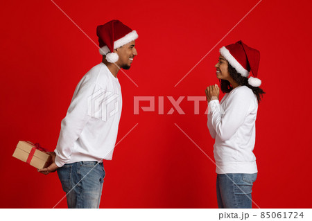 Loving black guy holding xmas gift for his excited girlfriend Loving black guy holding xmas gift for his excited girlfriend 85061724