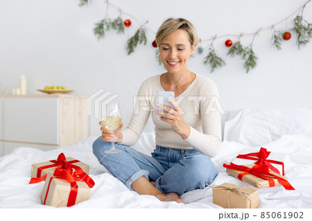 Happy lady using cellphone on Xmas drinking wine 85061902