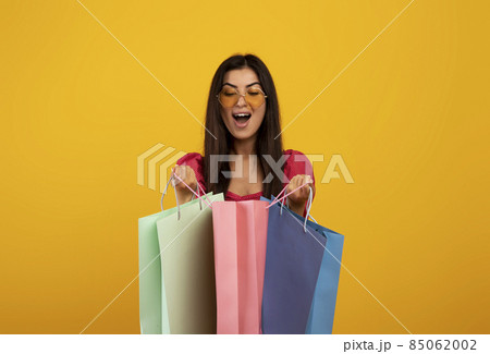 Satisfied customer. Excited armenian woman looking inside bright shopping bags, happy with her purchases Satisfied customer. Excited armenian woman looking inside bright shopping bags, happy with her purchases 85062002