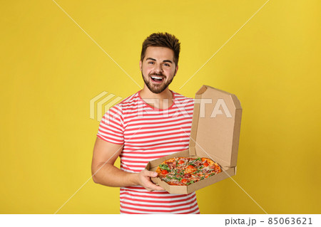Handsome man with tasty pizza on yellow background 85063621