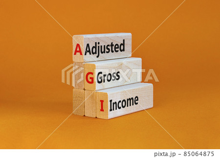 AGI adjusted gross income symbol. Concept words AGI adjusted gross income on wooden blocks. Beautiful orange table, orange background, copy space. Business and AGI adjusted gross income concept. 85064875
