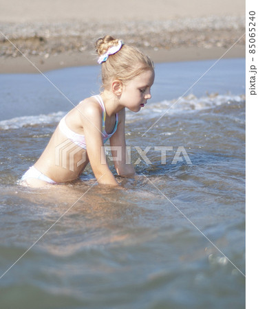 Little girl playing on the beach by the sea 85065240