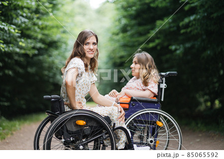 Young women in wheelchairs sitting at summer park 85065592