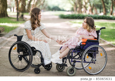 Ladies with disability looking on each other at green park Ladies with disability looking on each other at green park 85065631