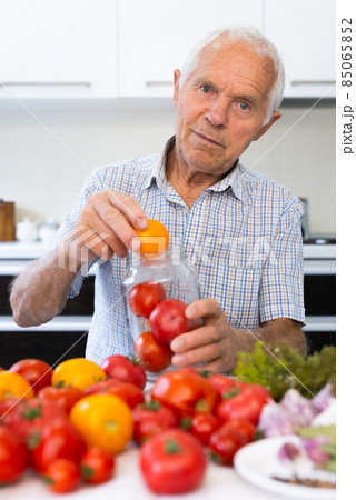 old gray haired man makes harvests for the winter pickles tomatoes 85065852