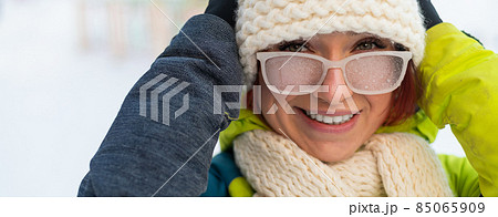 Caucasian woman with glasses smiling and freezing outdoors in winter. Caucasian woman with glasses smiling and freezing outdoors in winter. 85065909