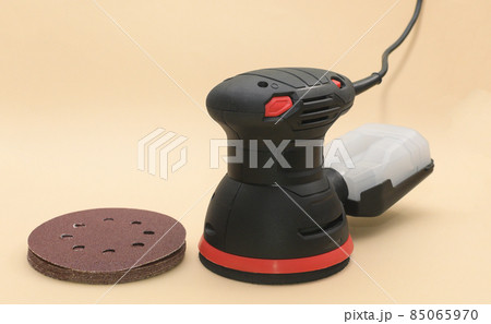 Eccentric orbital sander, with grinding wheels. grinder machine for wood with grinding wheel, close up. on a beige background. Eccentric orbital sander, with grinding wheels. grinder machine for wood with grinding wheel, close up. on a beige background. 85065970