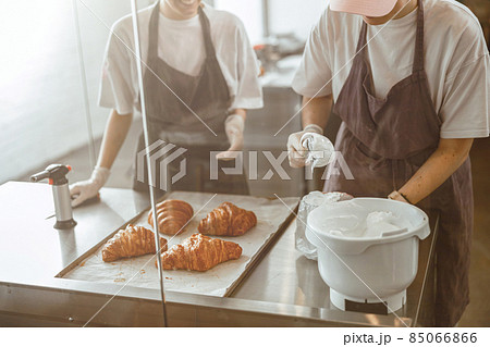 Worker fills confectioner with delicious cream at table with croissants in craft bakery shop Worker fills confectioner with delicious cream at table with croissants in craft bakery shop 85066866