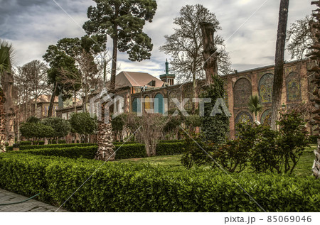 Conifers and palm trees wrapped for winter, clipped trunks of old trees on a green lawn in the Golestan garden in Tehran. Conifers and palm trees wrapped for winter, clipped trunks of old trees on a green lawn in the Golestan garden in Tehran. 85069046
