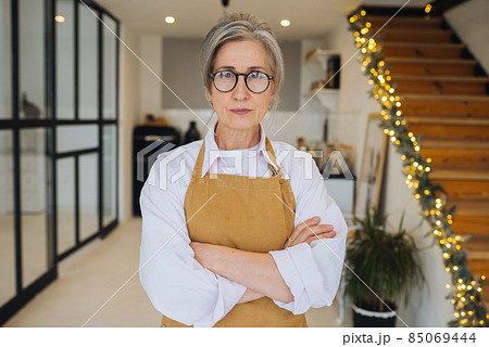 Portrait of strict granny standing in displeased pose staring angry at camera 85069444