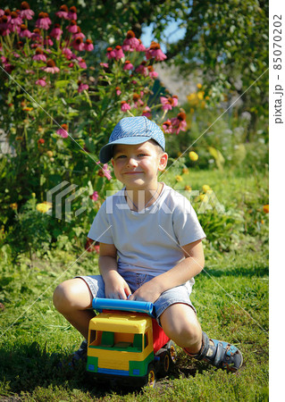 Boy playing outdoors with big toy car Boy playing outdoors with big toy car 85070202