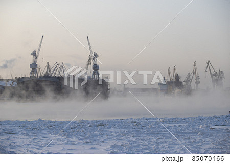 The construction of nuclear icebreakers, cranes of of the Baltic shipyard in a frosty winter day, steam over the Neva river, smooth surface of the river 85070466