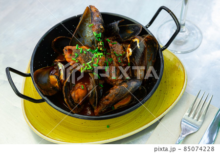 Stewed mussels in gravy with fresh chopped scallions Stewed mussels in gravy with fresh chopped scallions 85074228