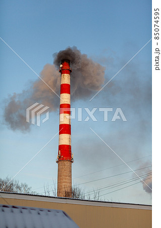 White thick smoke from the boiler room chimney. Smoke against the blue sky. Air pollution. Heating of the city. Industrial zone. 85074595