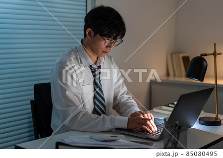 Overwork Concept The man sitting at his desk and focusing on working through his computer laptop Overwork Concept The man sitting at his desk and focusing on working through his computer laptop 85080495