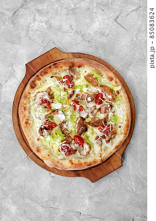 Delicious pizza Caesar style with white sauce, chicken, parmesan, egg, cherry tomatoes and fresh lettuce at wooden background. Restaurant pizzeria menu with delicious taste pizza Caesar. Delicious pizza Caesar style with white sauce, chicken, parmesan, egg, cherry tomatoes and fresh lettuce at wooden background. Restaurant pizzeria menu with delicious taste pizza Caesar. 85083624