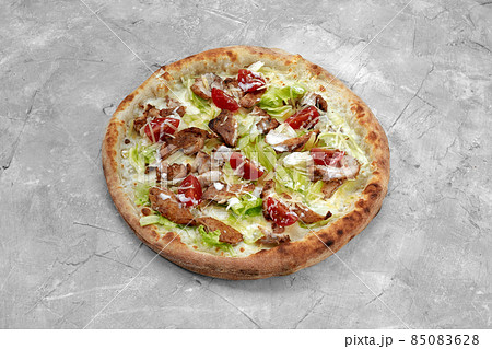 Delicious pizza Caesar style with white sauce, chicken, parmesan, egg, cherry tomatoes and fresh lettuce at wooden background. Restaurant pizzeria menu with delicious taste pizza Caesar. 85083628