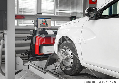 Tire clamped with aligner undergoing auto wheel alignment in garage. Tire clamped with aligner undergoing auto wheel alignment in garage. 85084420