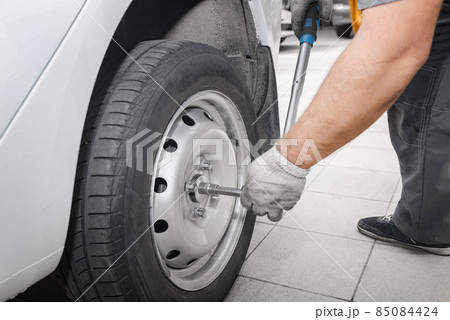Mechanician changing car wheel in auto repair shop. Mechanician changing car wheel in auto repair shop. 85084424