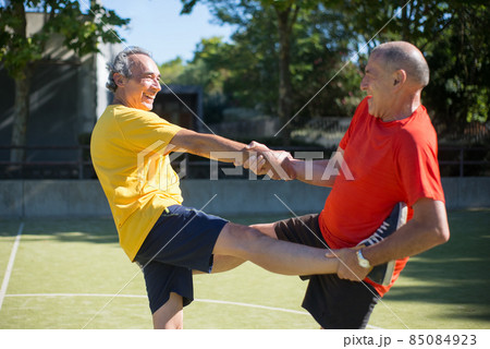 Helpful senior men getting ready for match on sunny day Helpful senior men getting ready for match on sunny day 85084923