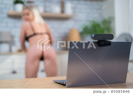 A girl in underwear flirts on an online video connection on a laptop. Woman working as a web cam model 85085846