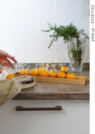 Tangerines on a wooden plate in a white kitchen Tangerines on a wooden plate in a white kitchen 85087562