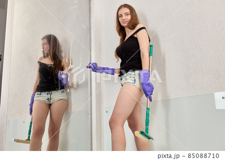 Maid washes large mirror in hotel bathroom. Maid washes large mirror in hotel bathroom. 85088710