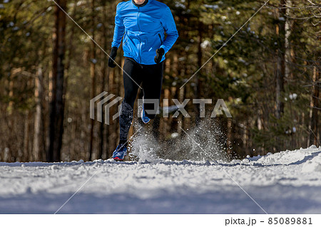 male athlete running on snowy trail in woods male athlete running on snowy trail in woods 85089881