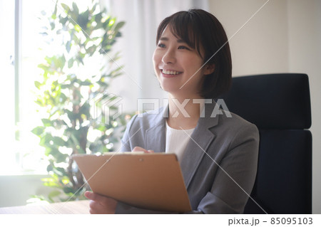 バインダーを持つ笑顔の女性社員 85095103