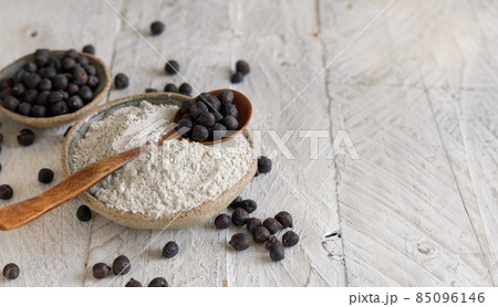 Bowl of black chickpea flour and beans with a wooden spoon closeup 85096146