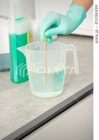 The beautician uses a stick to mix disinfectant into the water. Sterilization of tools. The beautician uses a stick to mix disinfectant into the water. Sterilization of tools. 85096899