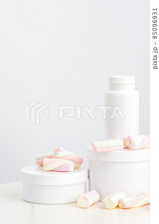 Cosmetic skincare packaging. Beauty product on white background. White jars with marshmallows on the white table. Cosmetic skincare packaging. Beauty product on white background. White jars with marshmallows on the white table. 85096931