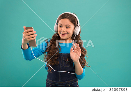 hello. kid long hair make selfie in headset. small child make play list on smartphone. hello. kid long hair make selfie in headset. small child make play list on smartphone. 85097393