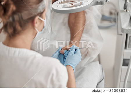 Specialist removes cuticle from toenail of man client with metal probe in salon Specialist removes cuticle from toenail of man client with metal probe in salon 85098634