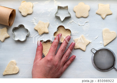 Top view of woman hands cooking a gingerbread cookie in the form of heart, star, cloud and flower. Christmas and New Year concept, festive preparations for winter hilodays Top view of woman hands cooking a gingerbread cookie in the form of heart, star, cloud and flower. Christmas and New Year concept, festive preparations for winter hilodays 85098922