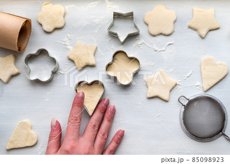 Top view of woman hands cooking a gingerbread cookie in the form of heart, star, cloud and flower. Christmas and New Year concept, festive preparations for winter hilodays 85098923