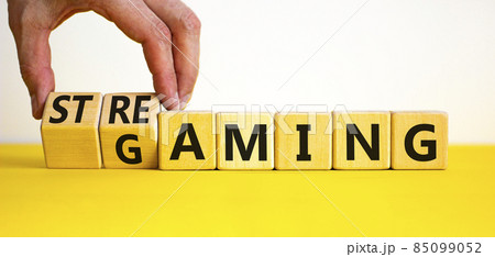Gaming and streaming symbol. Businessman turns wooden cubes and changes the word gaming to streaming. Beautiful yellow table white background, copy space. Business, gaming and streaming concept. 85099052
