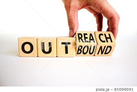Outreach or outbound symbol. Businessman turns wooden cubes and changes the word 'outbound' to 'outreach'. Beautiful white table, white background. Business, outreach or outbound concept. Copy space. Outreach or outbound symbol. Businessman turns wooden cubes and changes the word 'outbound' to 'outreach'. Beautiful white table, white background. Business, outreach or outbound concept. Copy space. 85099091