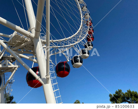 Closeup modern Ferris wheel against blue sky and white clouds. Ferris wheel at funfair for entertainment and recreation on holiday. Modern construction of Ferris wheel in amusement. Fun festival 85100633