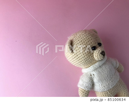 interior toy - a soft knitted bear on a pink background in the corner of the background. bear made of natural materials, crocheted of threads. cute gift interior toy - a soft knitted bear on a pink background in the corner of the background. bear made of natural materials, crocheted of threads. cute gift 85100634