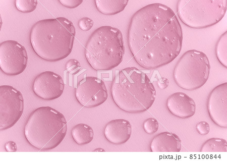 A pattern of pink doses of acid, hyaluronic moisturizing serum or gel on a monochrome background. Abstract backdrop pattern. Beauty product wallpaper. Cosmetics or healthcare protection concept.  85100844