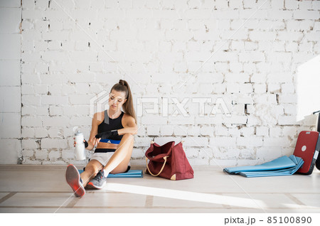 Female fighter exhausted after exercise feeling dehydration, drinks isotonic drink from bottle. Young woman rest after intense training in a boxing studio. 85100890