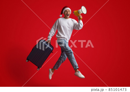 Man In Santa Hat Jumping With Suitcase And Making Announcement With Loudspeaker Man In Santa Hat Jumping With Suitcase And Making Announcement With Loudspeaker 85101473