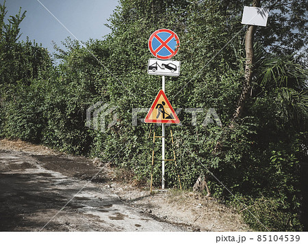 Traffic signs on the side of an uninterrupted road with trees along it Traffic signs on the side of an uninterrupted road with trees along it 85104539