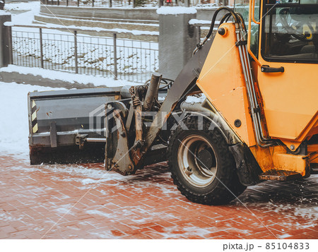 Fragment of orange bulldozer raking snow from tiles Fragment of orange bulldozer raking snow from tiles 85104833