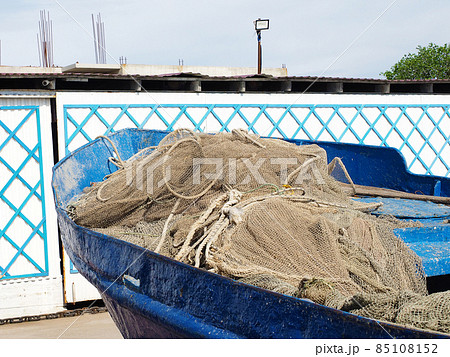 A rolledup fishing net lies in an old blue shabby boat in the bright sun outdoors A rolledup fishing net lies in an old blue shabby boat in the bright sun outdoors 85108152