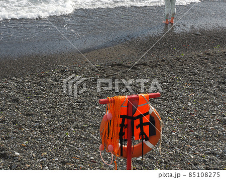 Orange rescue equipment hangs on the pebble beach of the foamy sea 85108275
